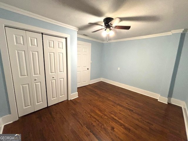 unfurnished bedroom with ornamental molding, dark hardwood / wood-style floors, ceiling fan, and a closet