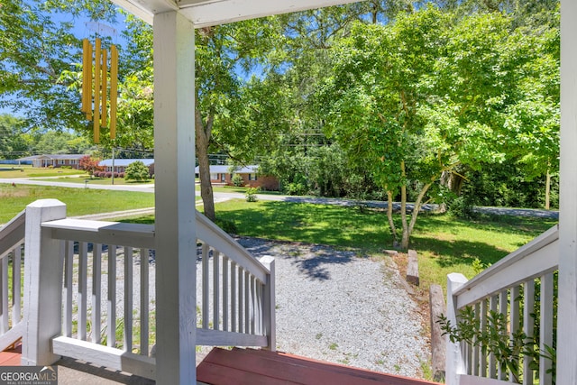 wooden terrace featuring a yard and covered porch