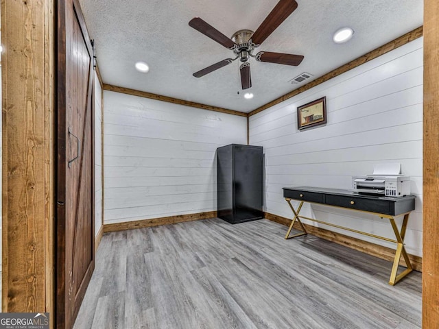 miscellaneous room with ceiling fan, a textured ceiling, and light wood-type flooring