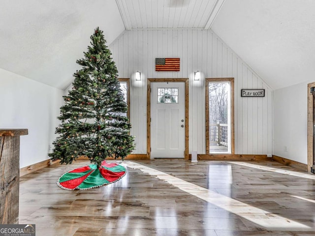 entrance foyer featuring wood walls, wood-type flooring, and lofted ceiling