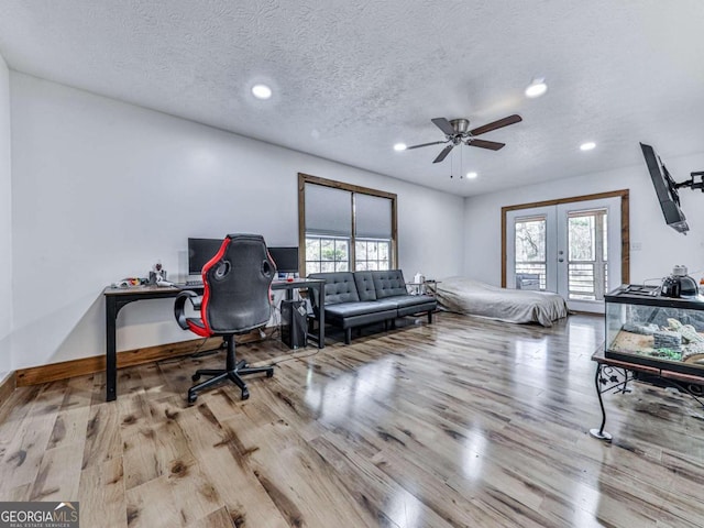 bedroom featuring a textured ceiling, light hardwood / wood-style flooring, french doors, and access to outside