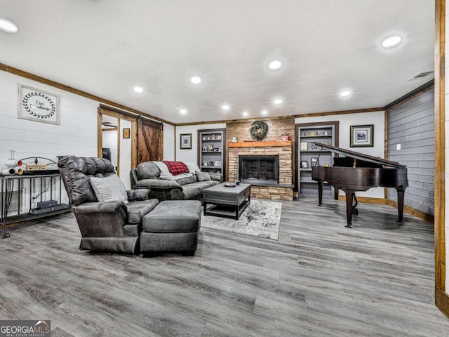 living room featuring a barn door, a fireplace, crown molding, and hardwood / wood-style floors