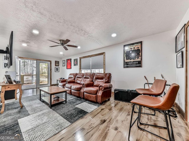 living room featuring light hardwood / wood-style flooring, a textured ceiling, and ceiling fan