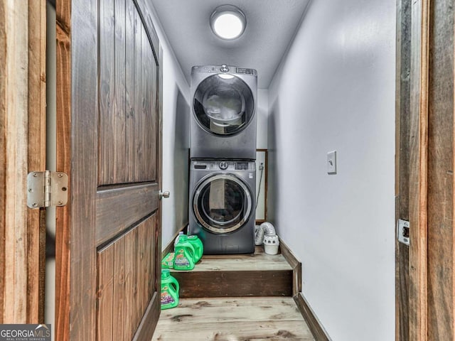 washroom with a textured ceiling, light hardwood / wood-style flooring, and stacked washer / drying machine