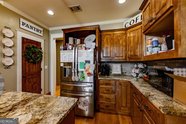 kitchen with light stone counters, ornamental molding, stainless steel fridge with ice dispenser, decorative backsplash, and light hardwood / wood-style floors