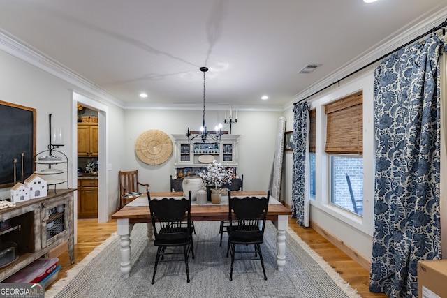 dining area featuring light hardwood / wood-style flooring, crown molding, and a notable chandelier