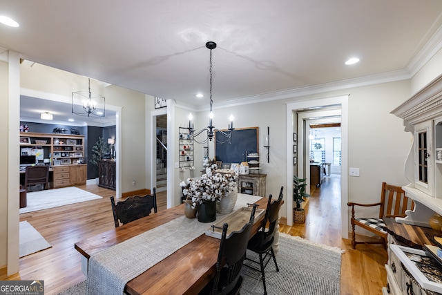 dining room featuring light wood-type flooring, crown molding, and a notable chandelier