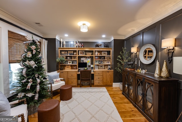 office area featuring built in desk, crown molding, and light hardwood / wood-style floors