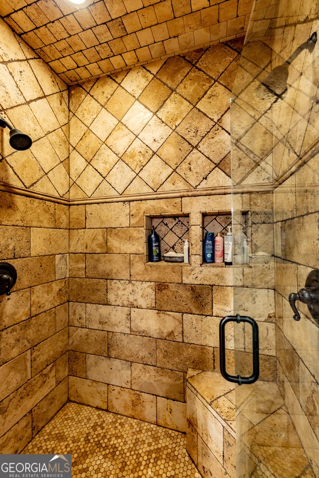 bathroom with brick ceiling and a shower with door