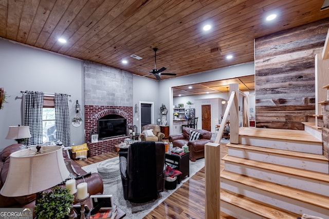 living room with a brick fireplace, hardwood / wood-style floors, ceiling fan, and wooden ceiling