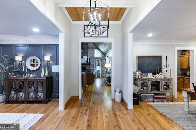 entryway featuring light wood-type flooring, a chandelier, and crown molding