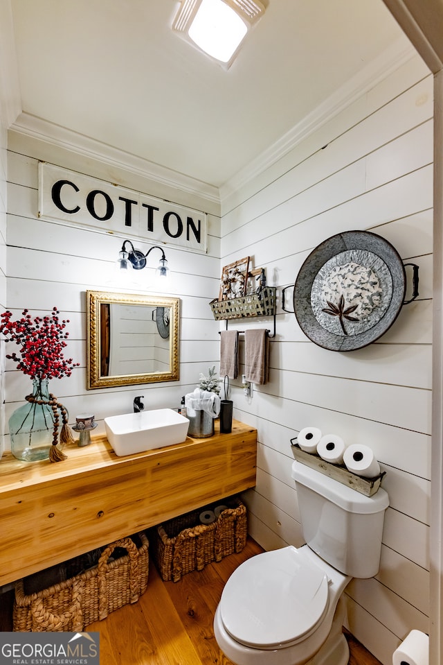 bathroom with hardwood / wood-style floors, vanity, crown molding, wooden walls, and toilet