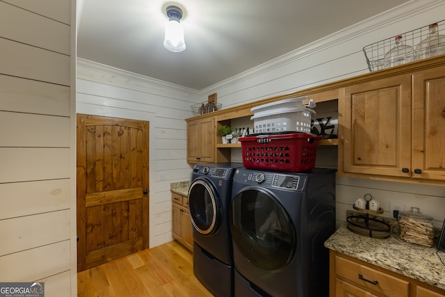 washroom featuring crown molding, wood walls, cabinets, independent washer and dryer, and light hardwood / wood-style flooring