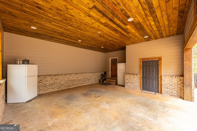 interior space featuring concrete flooring, wooden ceiling, and brick wall