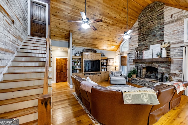 living room with ceiling fan, high vaulted ceiling, a fireplace, wood ceiling, and light wood-type flooring