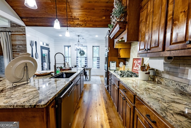 kitchen with stainless steel appliances, light hardwood / wood-style floors, wood walls, sink, and lofted ceiling