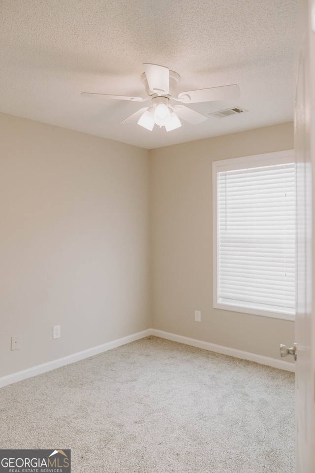 carpeted spare room with a textured ceiling and ceiling fan