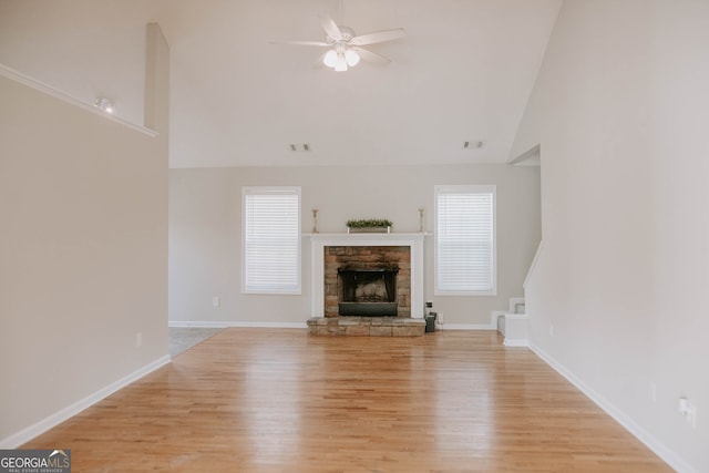 unfurnished living room with a fireplace, a healthy amount of sunlight, light hardwood / wood-style flooring, and high vaulted ceiling