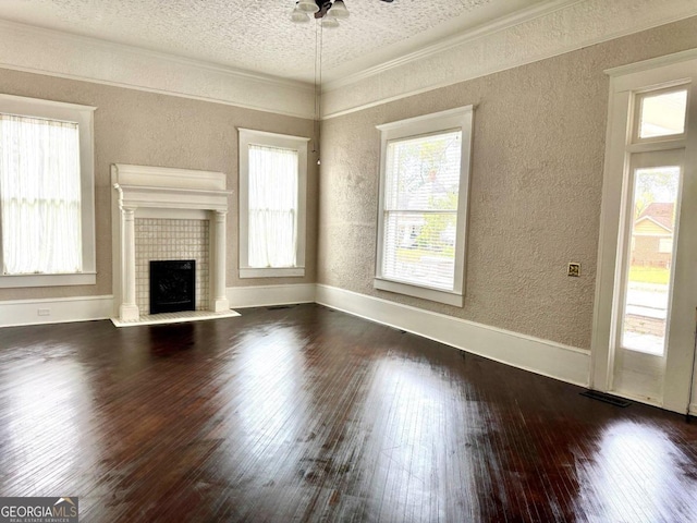 unfurnished living room with dark hardwood / wood-style flooring, a textured ceiling, ceiling fan, crown molding, and a fireplace