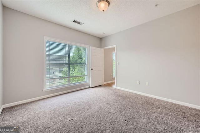 carpeted spare room with a textured ceiling