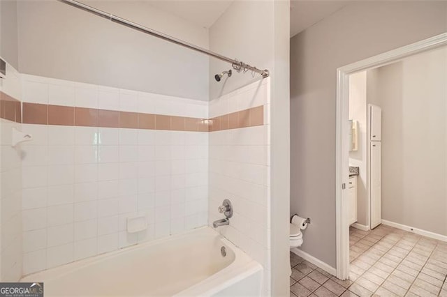 bathroom with toilet, tiled shower / bath, and tile patterned flooring