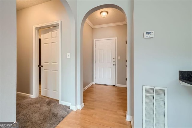 hall featuring ornamental molding, light hardwood / wood-style flooring, and a textured ceiling