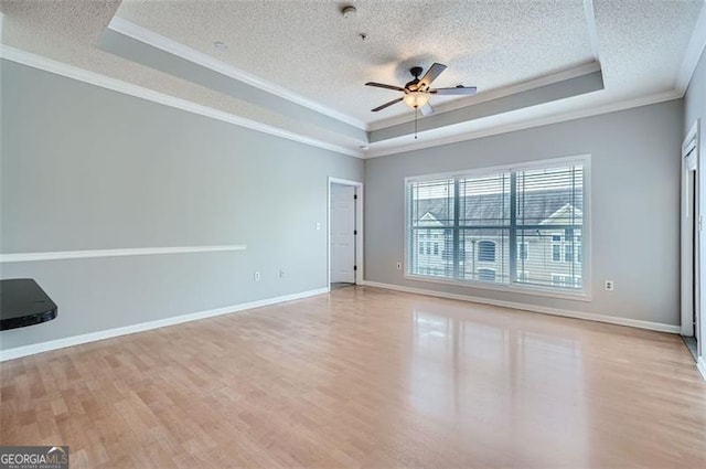 spare room featuring a textured ceiling, ceiling fan, crown molding, a raised ceiling, and light hardwood / wood-style flooring