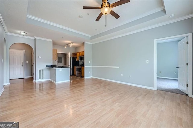 unfurnished living room featuring light hardwood / wood-style floors, crown molding, and a tray ceiling