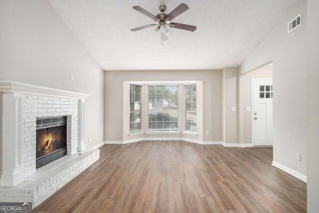 unfurnished living room featuring dark hardwood / wood-style flooring, a textured ceiling, ceiling fan, and a fireplace