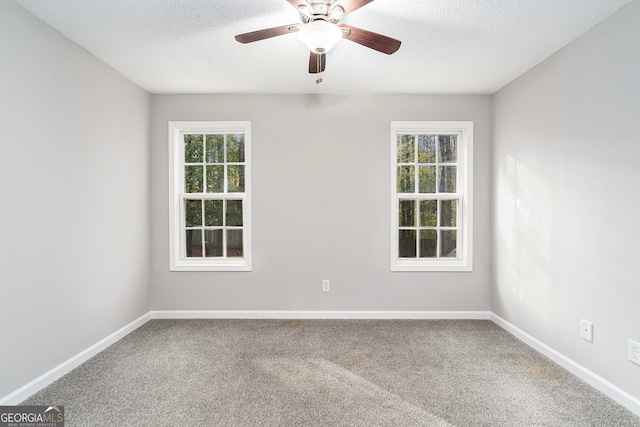 empty room with ceiling fan, carpet floors, a healthy amount of sunlight, and a textured ceiling