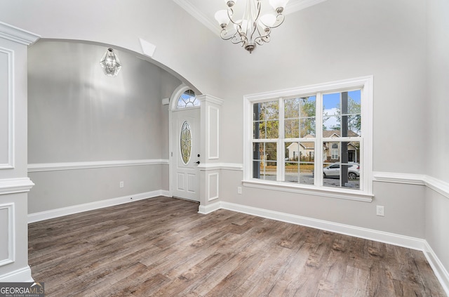 foyer with ornamental molding, a chandelier, and dark hardwood / wood-style flooring