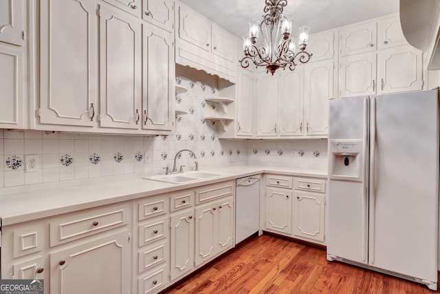 kitchen featuring sink, white cabinetry, light wood-type flooring, pendant lighting, and white appliances