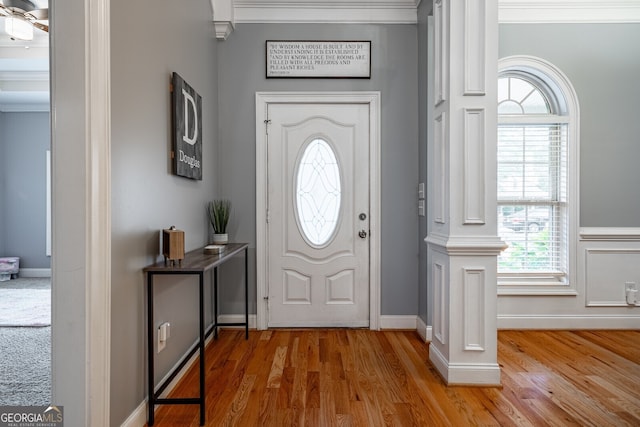 entrance foyer featuring hardwood / wood-style flooring, ceiling fan, ornate columns, and ornamental molding