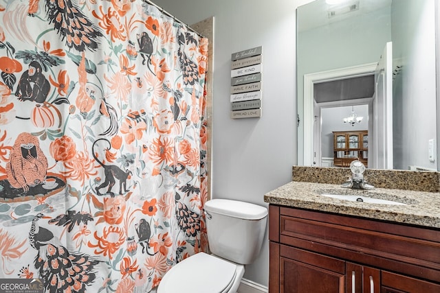 bathroom with toilet, vanity, and an inviting chandelier