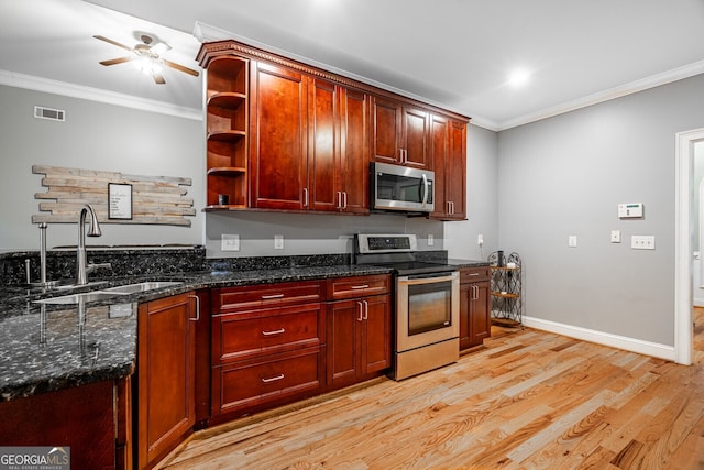 kitchen with sink, dark stone countertops, light wood-type flooring, ornamental molding, and stainless steel appliances