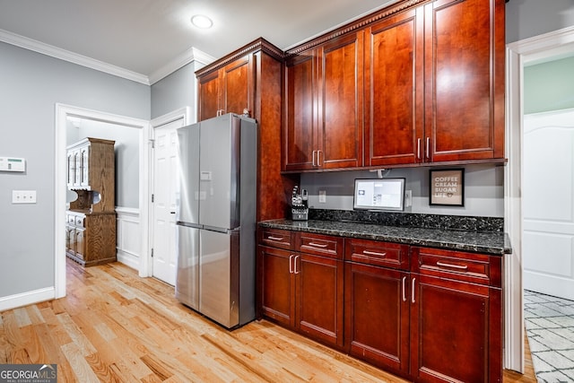 kitchen featuring stainless steel fridge, light hardwood / wood-style flooring, crown molding, and dark stone countertops