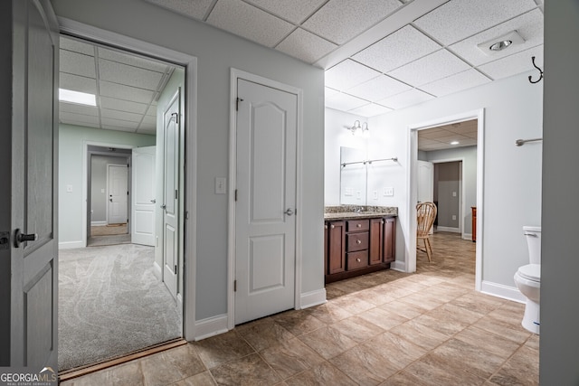 bathroom with a paneled ceiling, vanity, and toilet