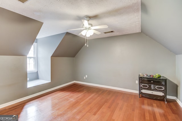 additional living space with hardwood / wood-style floors, a textured ceiling, and lofted ceiling