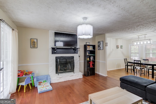 living room featuring a textured ceiling, a large fireplace, and hardwood / wood-style flooring