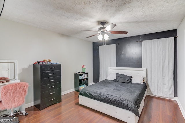 bedroom with dark wood-type flooring, ceiling fan, and a textured ceiling