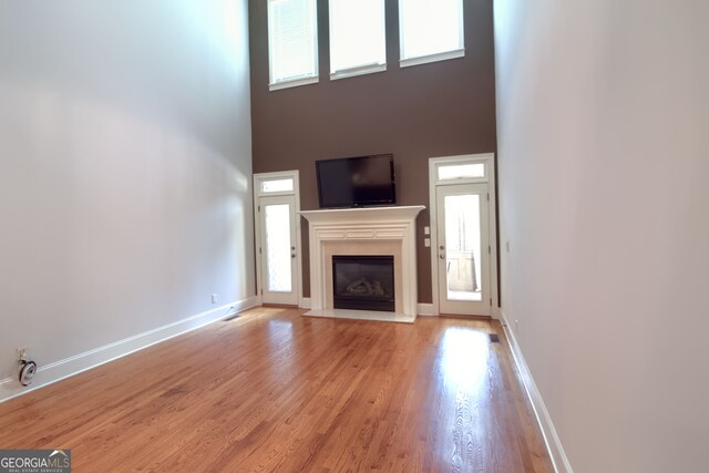 unfurnished living room with a healthy amount of sunlight, a high ceiling, and light wood-type flooring