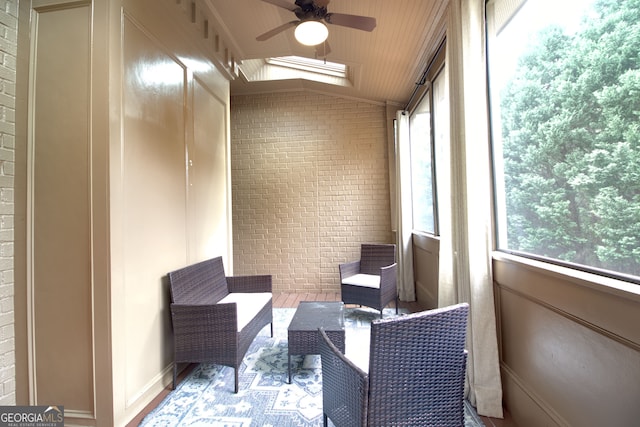 sunroom / solarium featuring ceiling fan and vaulted ceiling with skylight