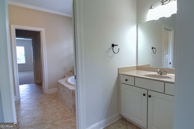 bathroom featuring tile patterned flooring, vanity, tiled bath, and crown molding