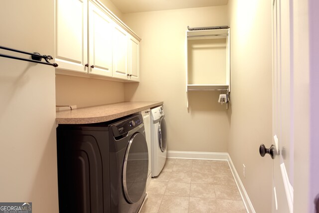 washroom featuring washing machine and dryer, light tile patterned floors, and cabinets