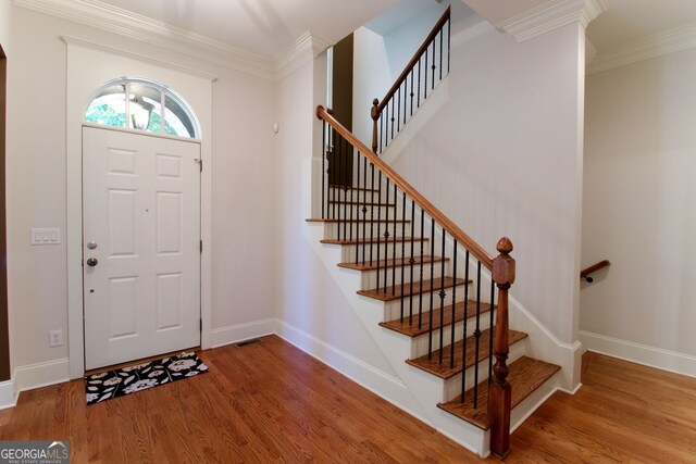 entrance foyer with ornamental molding and hardwood / wood-style flooring