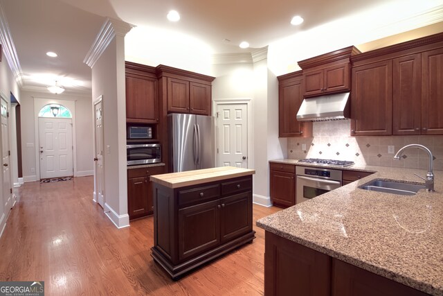 kitchen featuring backsplash, sink, light hardwood / wood-style flooring, ornamental molding, and stainless steel appliances