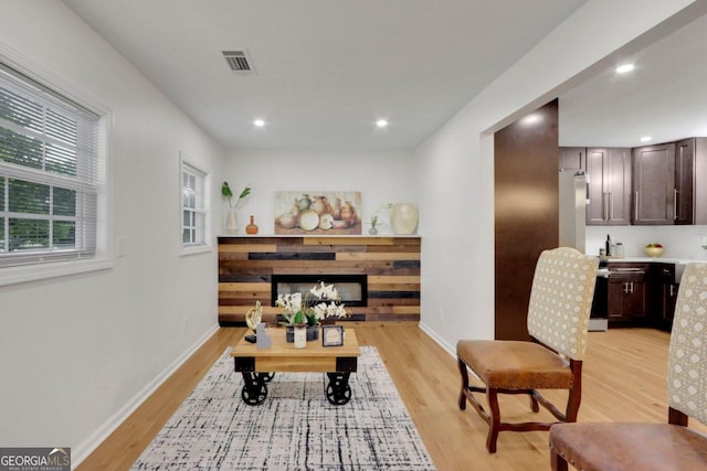 sitting room with light wood-style floors, a fireplace, and baseboards