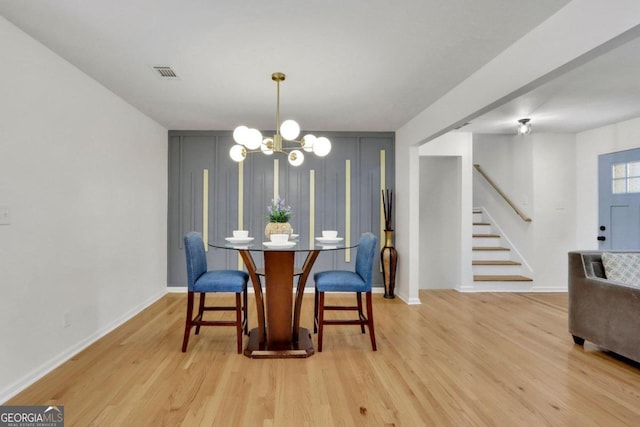 dining space featuring stairs, light wood-type flooring, visible vents, and an inviting chandelier