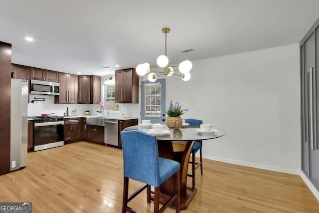 kitchen featuring a notable chandelier, stainless steel appliances, light countertops, light wood-type flooring, and baseboards