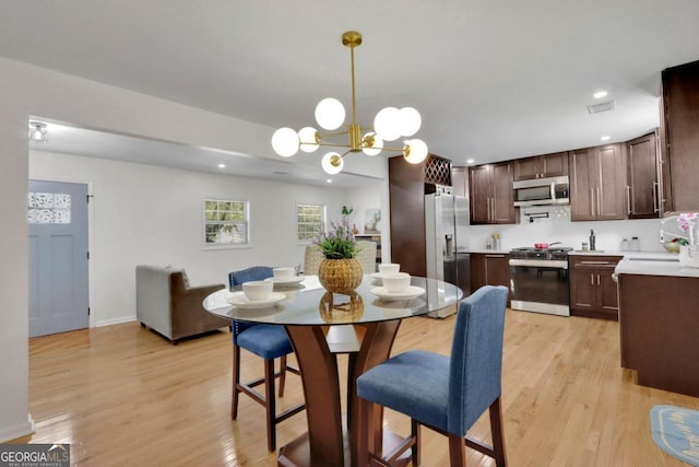 dining space with recessed lighting, light wood-type flooring, visible vents, and a notable chandelier